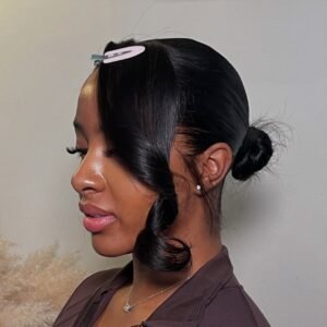 profile of a woman with a sleek black low bun and a curled side-swept fringe.