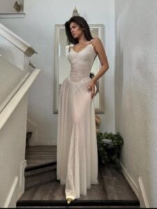 woman in sheer white maxi dress standing on carpeted staircase