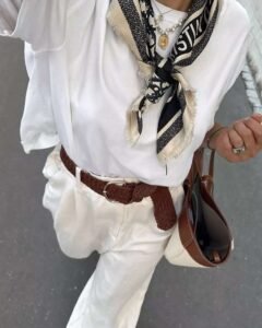woman wearing a white top and trousers styled with a patterned silk neck scarf