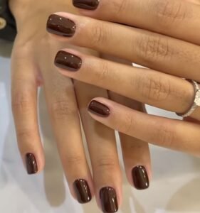 dark espresso brown gel polish on short square nails with a shiny reflective topcoat.