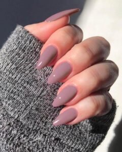 long mauve almond shaped nails with a glossy finish paired with a grey knit sweater.