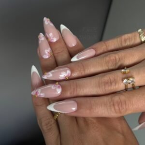 long stiletto nails with white french tips and pink floral nail art and gold rings