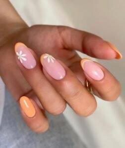 orange and pink almond nails with white daisy floral accents on a hand