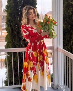 woman in a red floral print maxi dress holding a bouquet of orange tulips outdoors