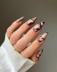 long pointed stiletto nails with brown and white marble swirl design on a hand