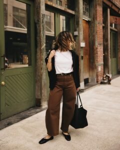 woman wearing brown barrel jeans, white t-shirt, black cardigan, and black ballet flats.