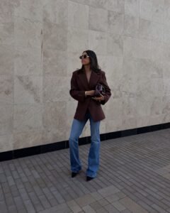 woman in brown oversized blazer and blue flare jeans walking outdoors