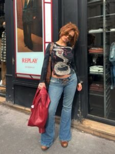 woman with red hair in snake print long sleeve shirt and flared jeans on city street