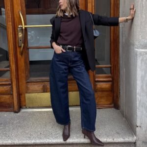 person wearing dark wash barrel jeans, brown sweater, black blazer, and pointed ankle boots.