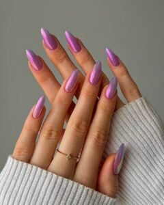 iridescent purple and pink chrome almond nails on hands wearing a white sweater.