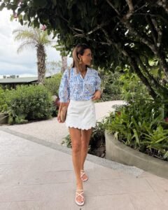 woman in blue and white tropical print blouse and white scalloped mini skirt outdoors