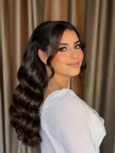 brunette woman with long glamorous waves and a soft side part bridal look