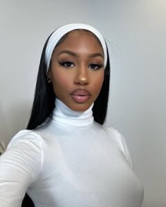 woman with long black hair wearing a white headband and turtleneck