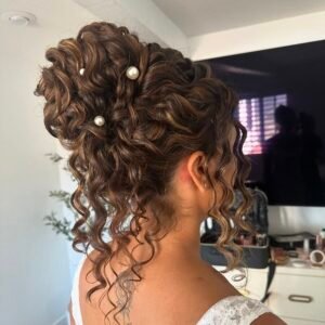 curly brunette bridal updo with pearl accents and long spiral tendrils falling down