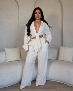 woman posing in a white long sleeve tie front top and matching wide leg trousers