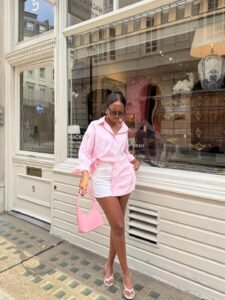 woman in a pink button-down shirt and white mini skirt holding a pink handbag.