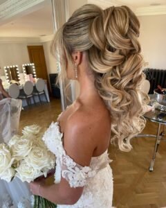 high voluminous curly blonde ponytail on a bride holding a white rose bouquet
