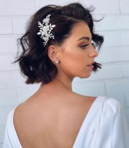 side profile of a woman with short wavy brunette hair and floral clip