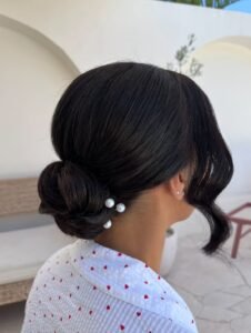 simple low brunette bun bridal hairstyle accented with three delicate white pearls