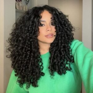 woman with voluminous dark curly hair wearing a bright green sweatshirt