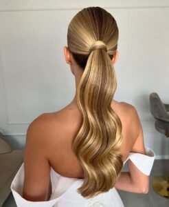 sleek blonde low ponytail with perfect waves for a modern bridal hairstyle
