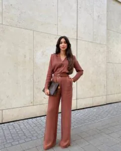 woman in a monochromatic copper button-down shirt and matching wide-leg trousers standing outdoors.