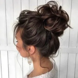 side profile of a woman with a large messy bun and gold earrings.