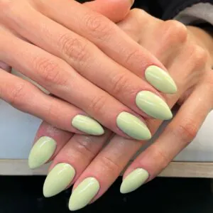 light green pastel stiletto nails on hands resting over a white surface