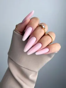 close-up photo of a hand featuring long, almond-shaped gel nails in a soft, creamy bubblegum pink.