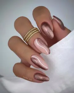 almond nails with rose gold magnetic cat eye polish and white swirl accents.