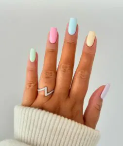 square nails painted in multi colored pastel shades of green pink blue and yellow