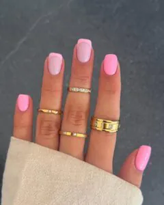 short square light pink nails with french tips and multiple gold rings.