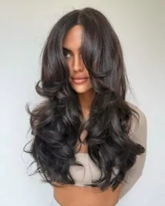 woman with voluminous dark brown layered hair and soft bouncy curls.