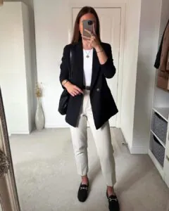 woman wearing a black blazer, white top, cream trousers, and black loafers for work outfit