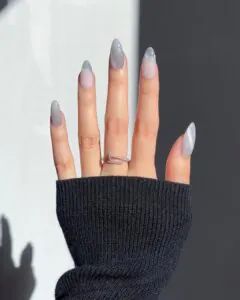 long almond nails with grey cat eye tips and a silver nail ring.