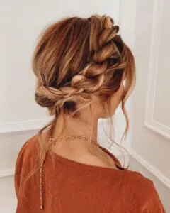 blonde rope crown braid updo on a woman wearing an orange shirt