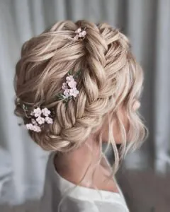blonde halo braid updo decorated with small pink flower hair accessories