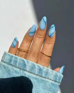 light blue nails with dark blue marble swirls and gold chain link ring.
