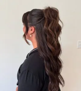 side view of a woman with a long brunette half-up ponytail hairstyle.