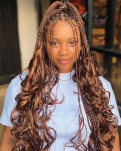 woman with long copper-colored french curl braids and a half-up ponytail.
