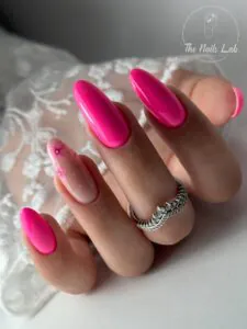 vibrant hot pink almond nails with one floral accent nail and silver ring