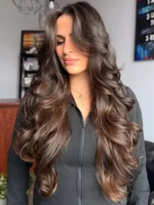 woman with very long dark brown hair styled in soft voluminous waves.