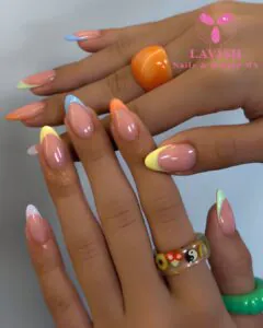 multicolored pastel french tip nails with various colorful rings on fingers