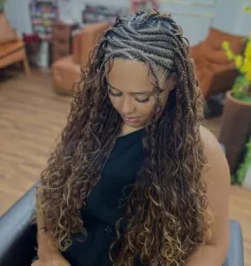 long honey blonde fulani braids with voluminous curly extensions in a salon setting
