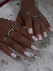 square milky white gel nails on dark skin with silver heart rings