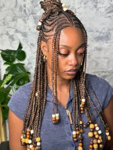 woman with half-up brown fulani braids featuring colorful wood beads and a top knot