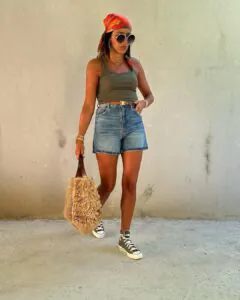woman wearing olive tank top, denim shorts, orange headscarf, and high-top sneakers.