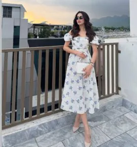 woman in floral print summer dress with puff sleeves standing on a rooftop balcony