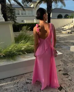 woman in pink one shoulder gown with floral strap standing in a stone courtyard