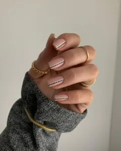 nude manicure with a vertical black and white dotted line design on square shaped nails.